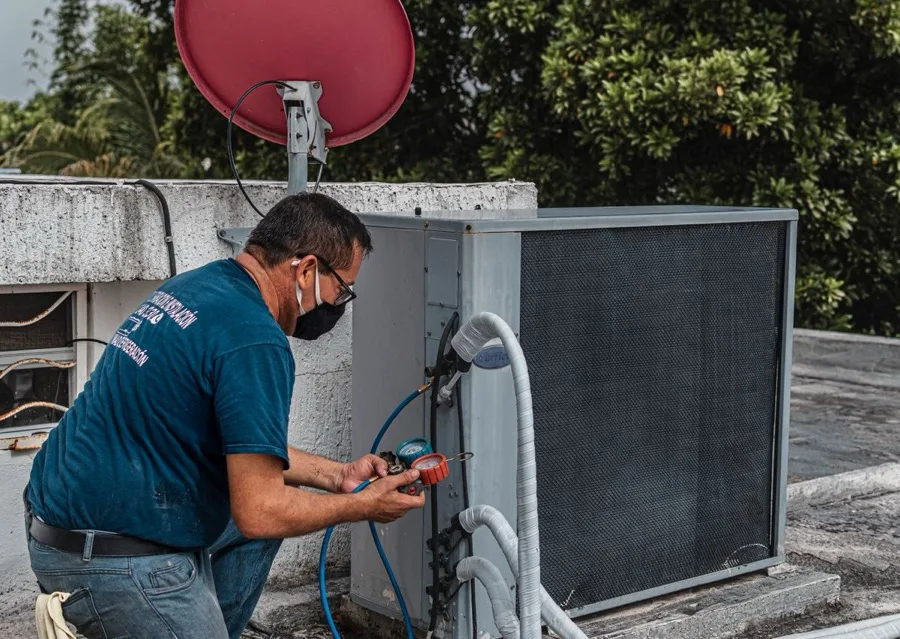 Bucca Fix technician servicing an outdoor condenser unit with refrigerant gauges